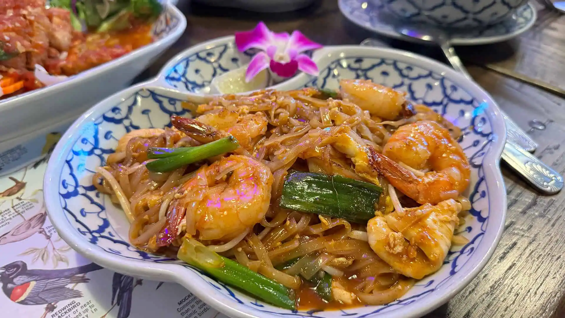 a shrimp pad thai in a large blue and white bowl