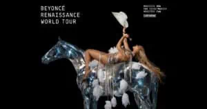 beyonce laying back on a silver horse statue while holding a white cowboy hat in the air on an all black background