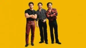 the Jonas Brothers stand on a yellow background