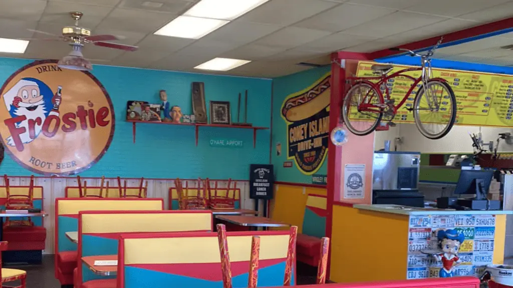 inside a restaurant with blue walls, a bike hangs from the ceiling. Retro decor is hung around the tables