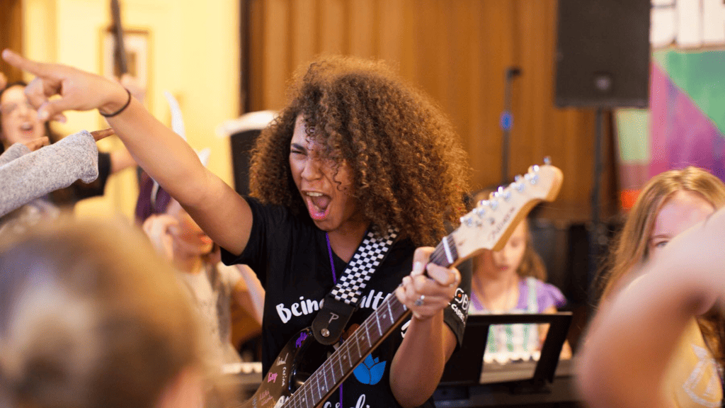 young girl on stage playing the guitar and signing in front of a crowd