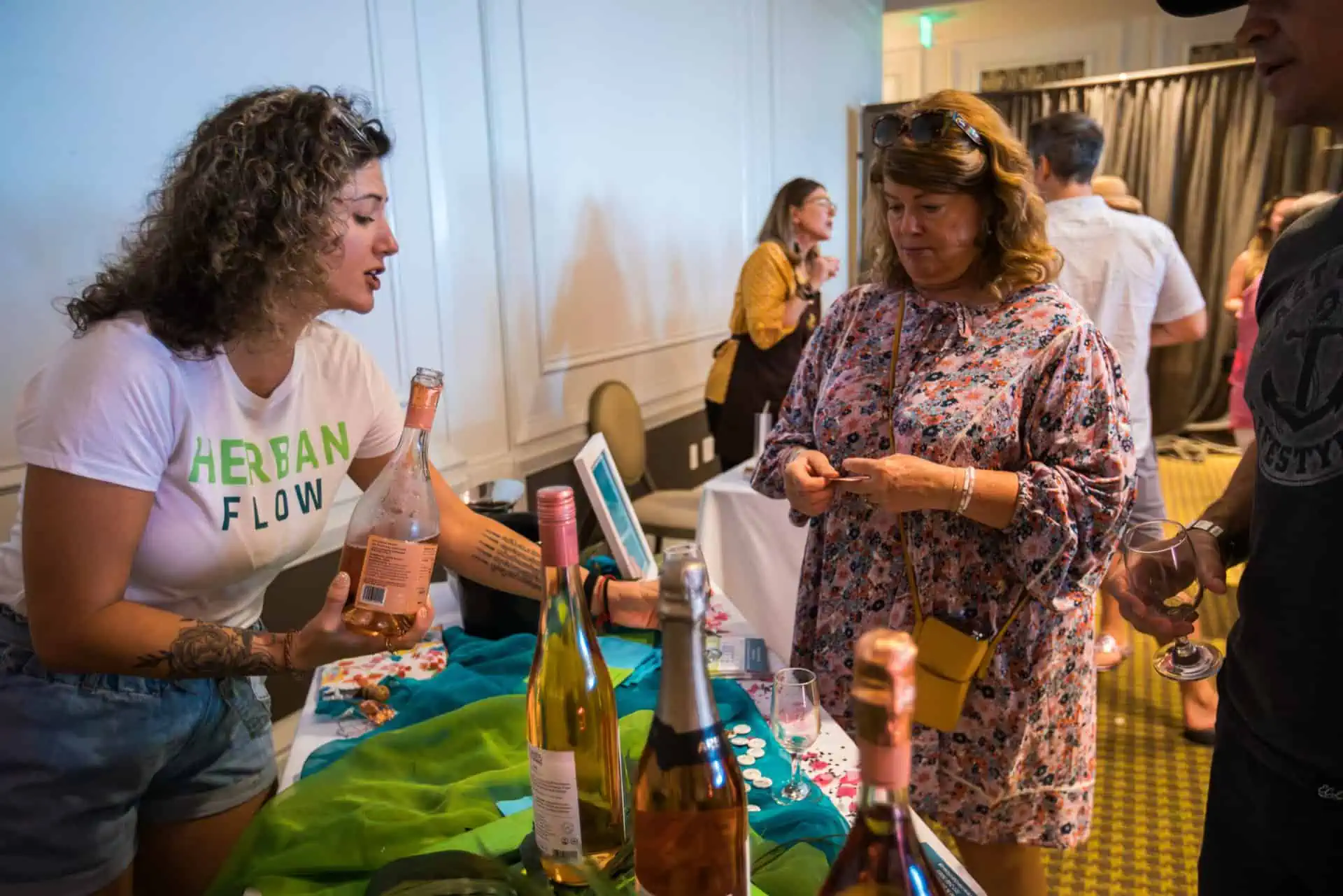 Herban Flow staff member pours nonalcoholic rosé wine for a guest at the event