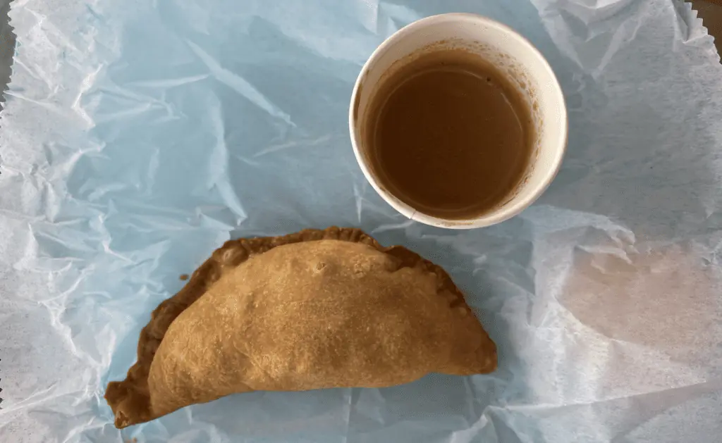 Empanada next to a shot of espresso on an outdoor table