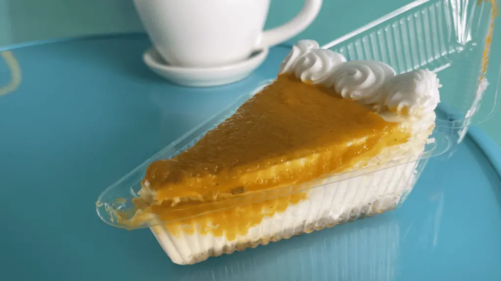 slice of mango cheesecake on a blue table