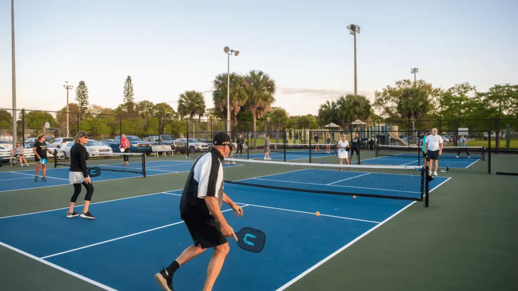 a group of people black on a green and blue pickleball court.