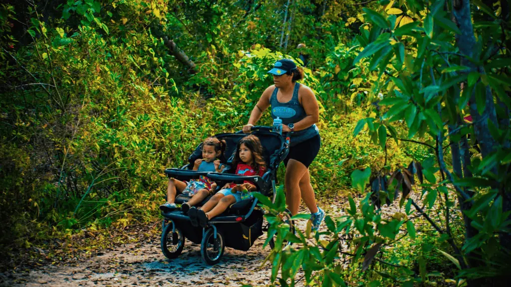 a mom pushing a stroller in a park on a trail run