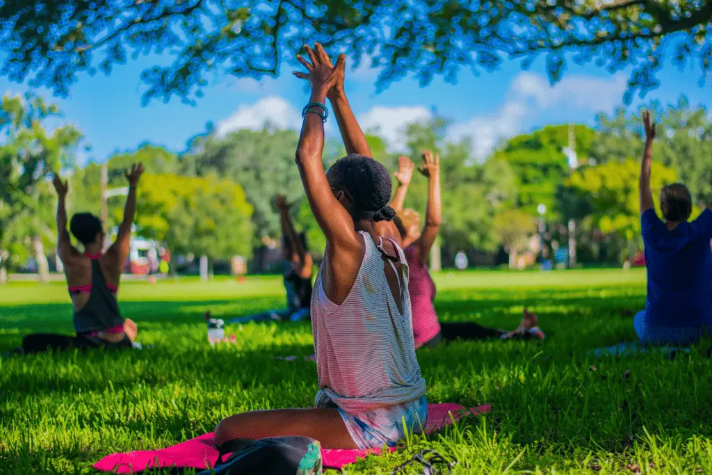 a group of people practice yoga in the grass at a park