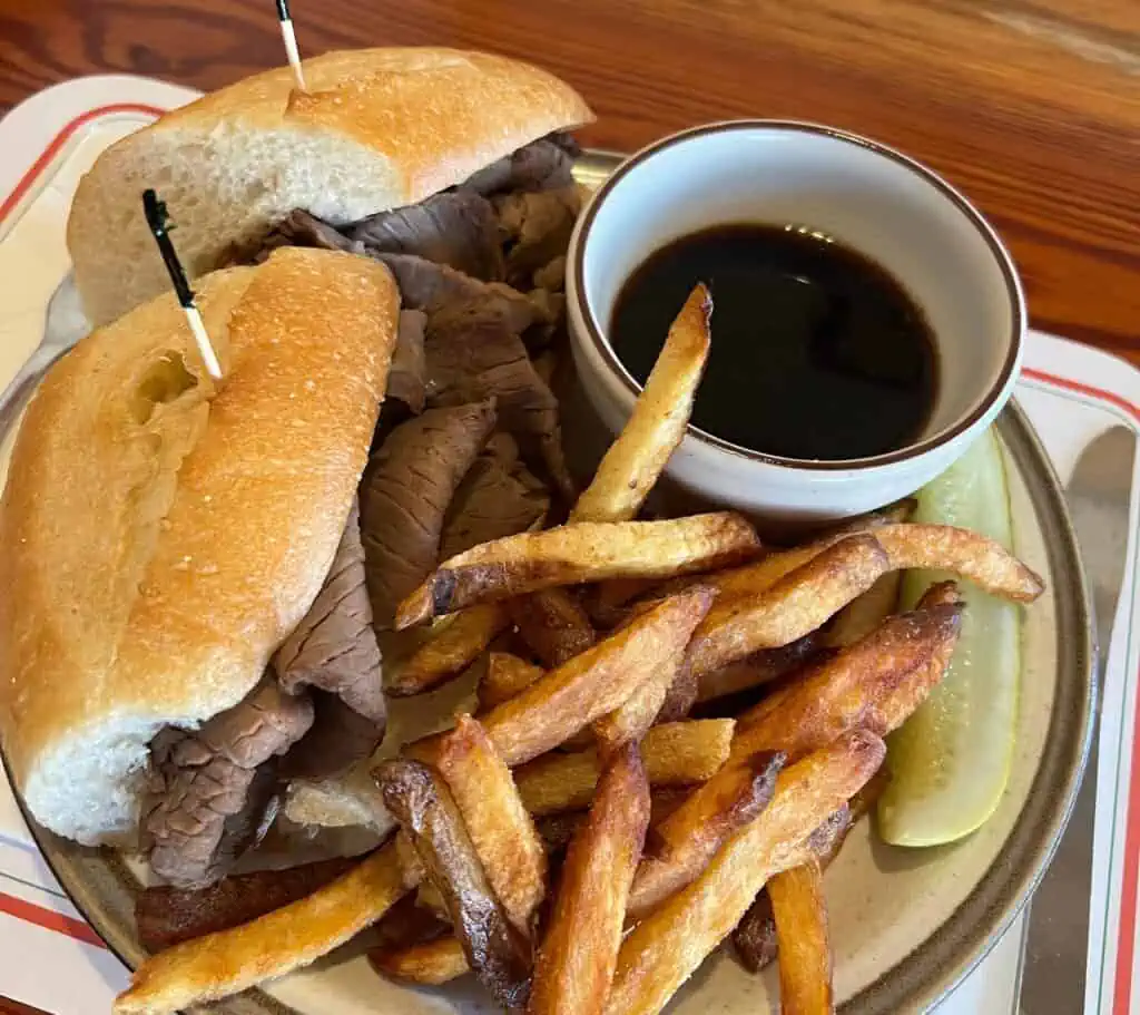 a roast beef sandwich with fries and a dipping sauce