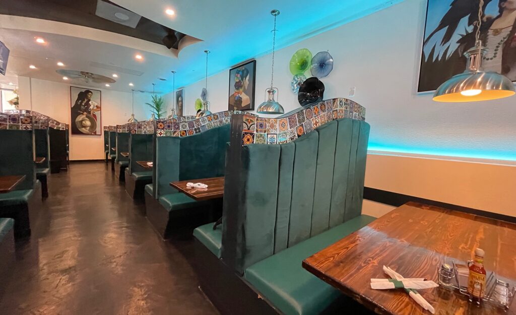 inside a restaurant with velvet booths, and glass art on the wall