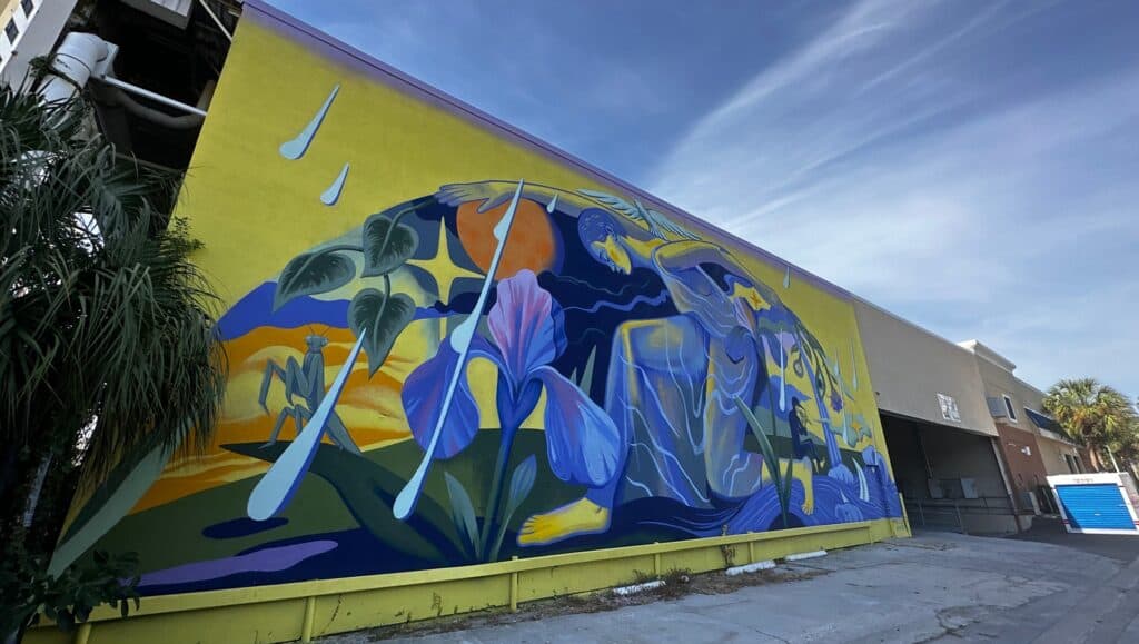 a yellow and blue mural on the side of a warehouse