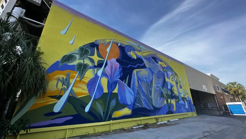 a yellow and blue mural on the side of a warehouse