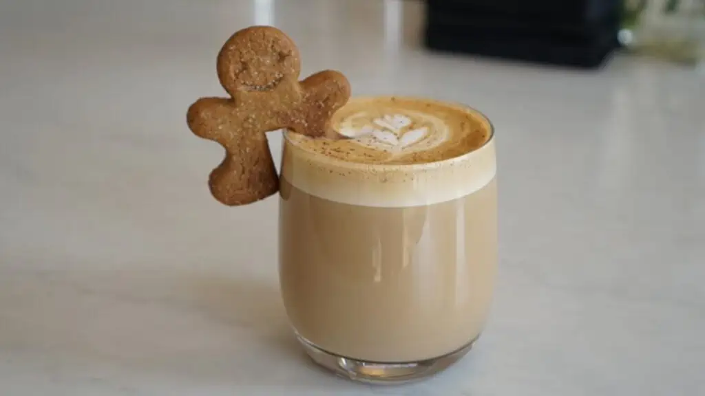 a small gingerbead man cookie sits on the edge of a coffee drink