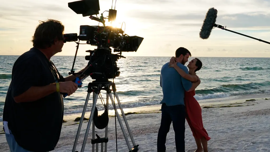 two people on the beach surrounded by camera crews