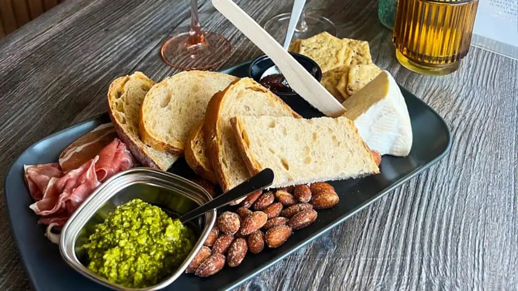 a build your own charcuterie board with bread, pesto, prosciutto, nuts, and crackers