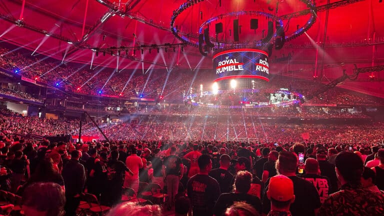 a large crowd inside a stadium surrounding a wrestling ring