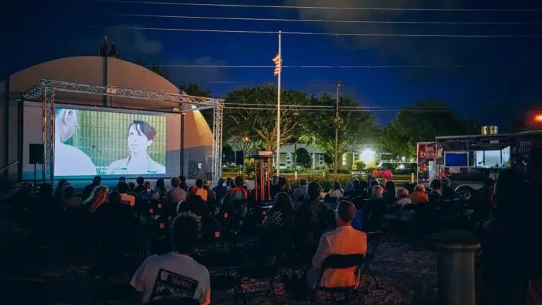 a group of people watch a film under the stars in a local arts district