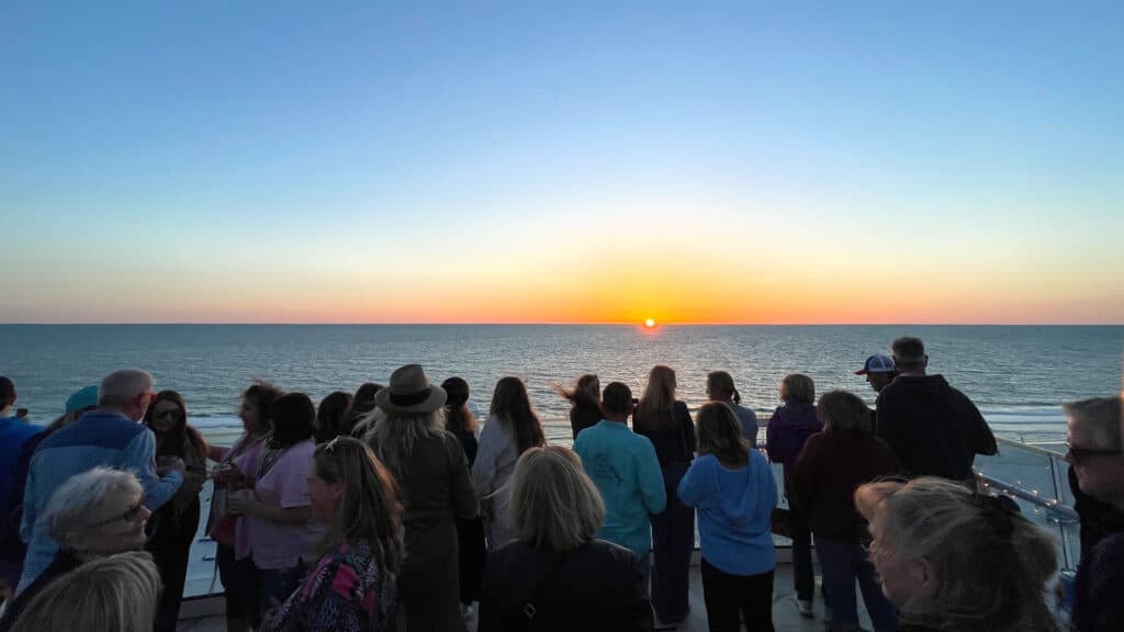 a crowd watches the sunset from 11 floors up on the rooftop of the Bellwether beach resort