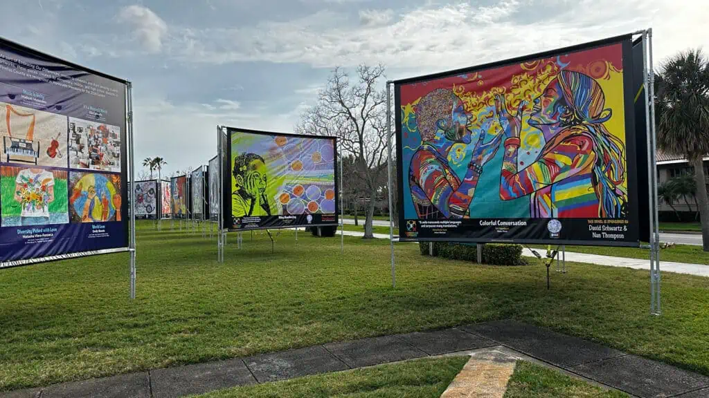 multiple banners with art on them arrange in a waterfront park.
