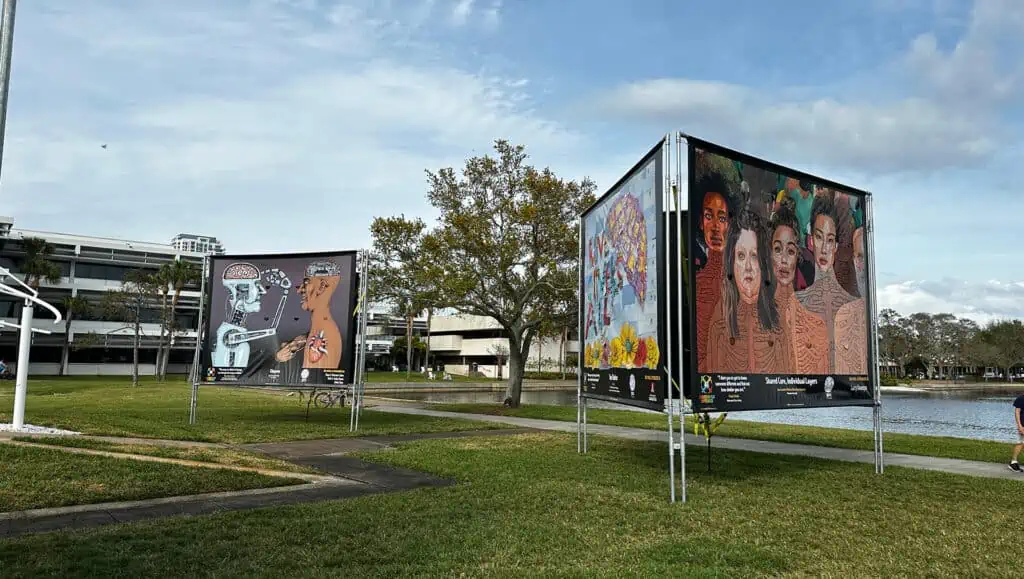 tree sided panels showcasing different works of art in a park