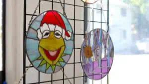 a kermit the frog wearing a santa hat stained glass art piece