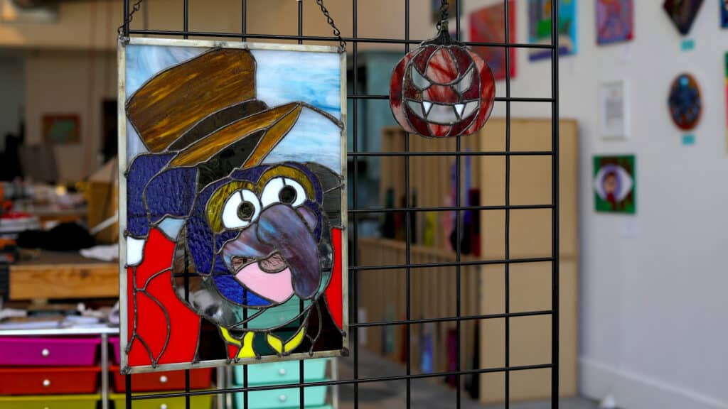 a gonzo stained glass art hangs next to a jack o lantern piece