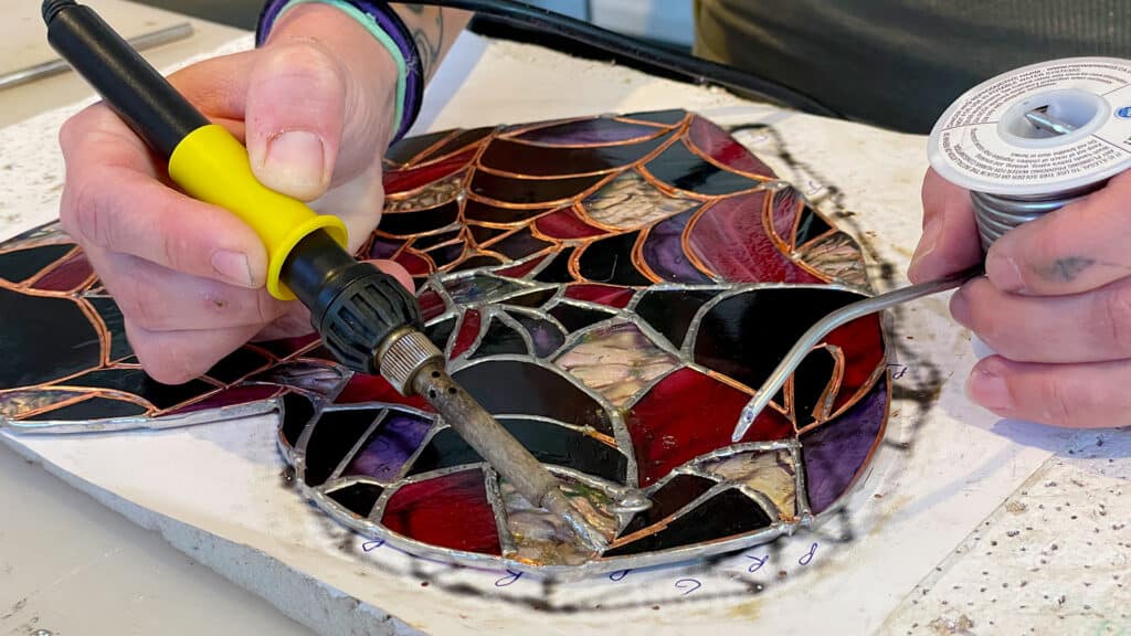 Artist Jodi Chemes solders a stained glass heart