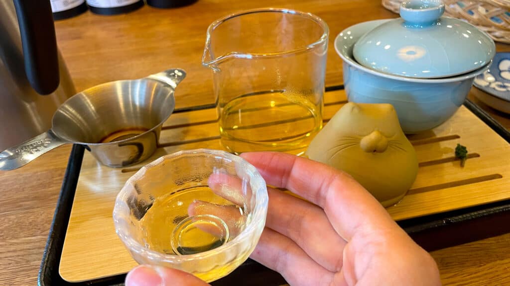 a hand holds a small teacup for a gongfu cha tea ceremony