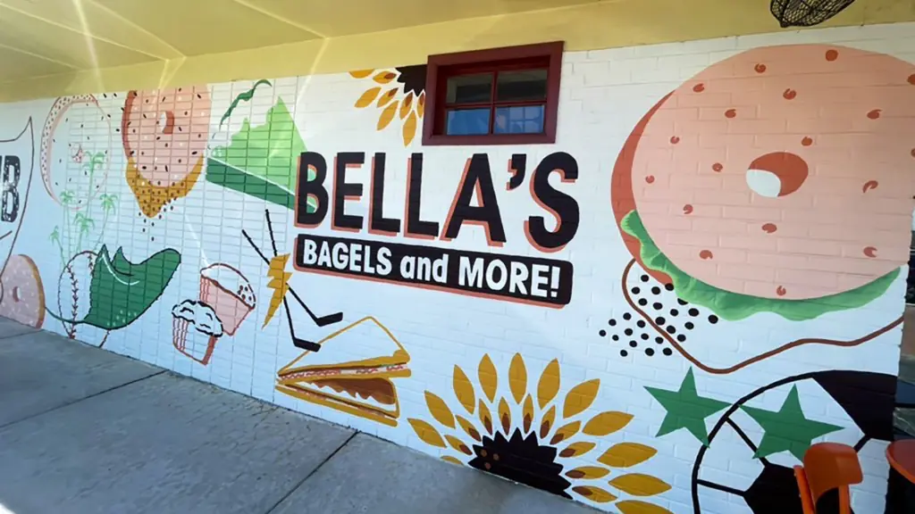 outside a bagel cafe with a colorful mural on the side of the building