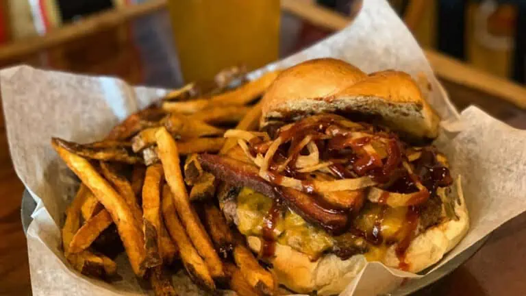 Burger and fries in a basket next to a glass of beer