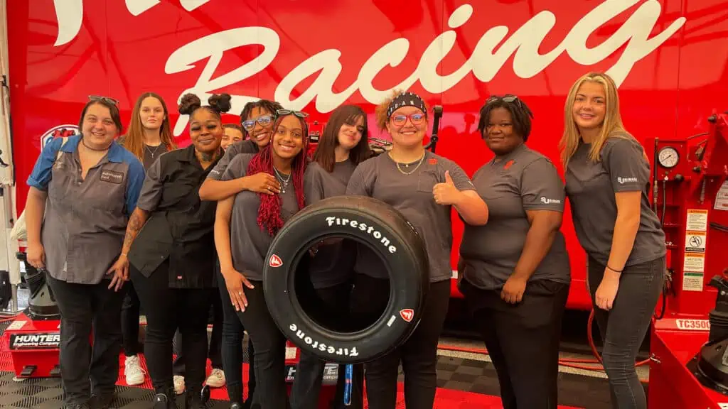 students from northeast high school and pinellas technical college holding up a firestone tire