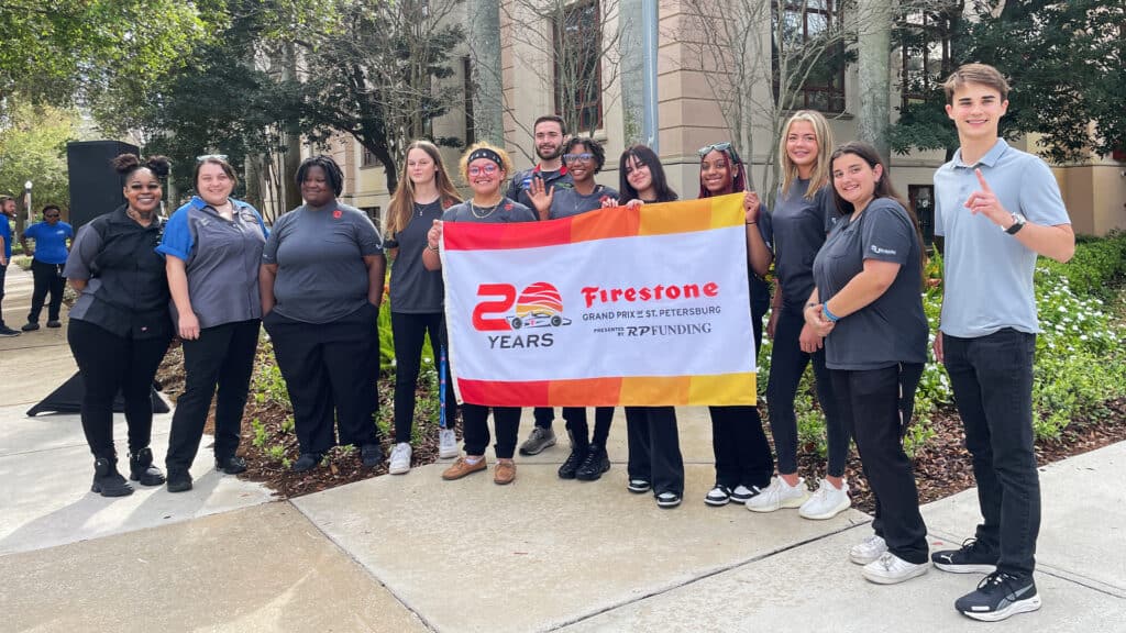 Students posing with the Firestone Grand Prix flag
