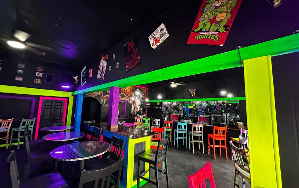 A multi color black light art room with neon colored chairs 