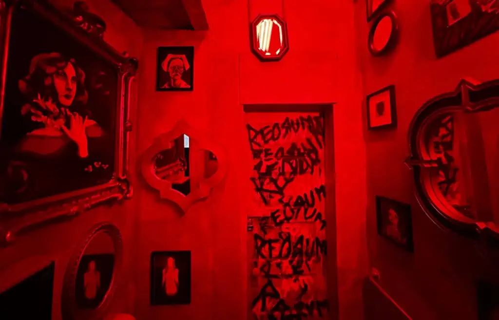 a bathroom with red lights turned on. Paintings are hung on both walls