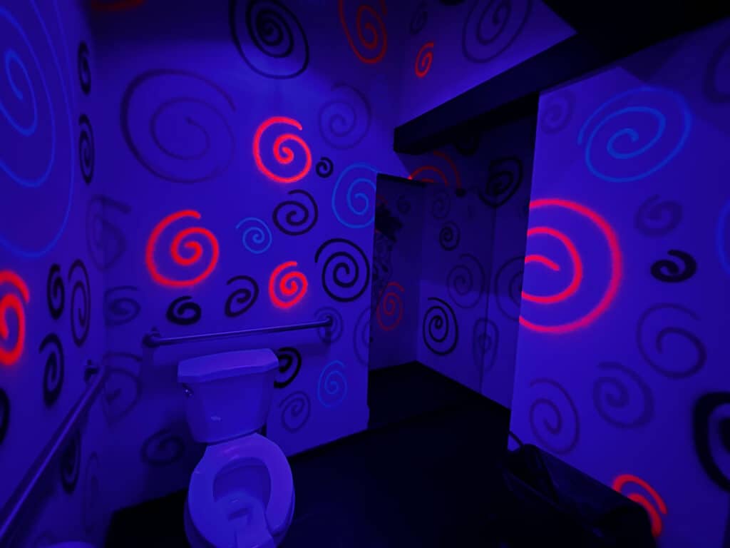 inside a bathroom with black light art all over the walls