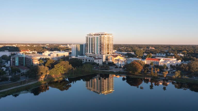 an aerial view of a condo tower that's reflected in mirror lake