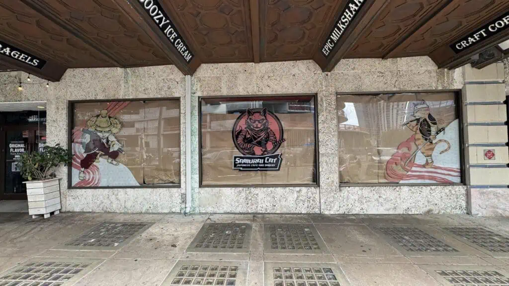 exterior of a restaurant with butcher paper in the window. Signage indicates the restaurant is named Samurai Cat