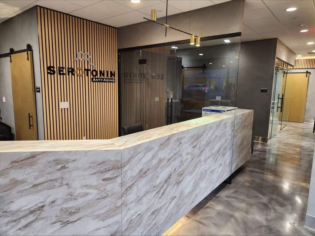 A look inside a Serotonin Center in Texas. Marble style reception desk with computer screen and subtle lighting