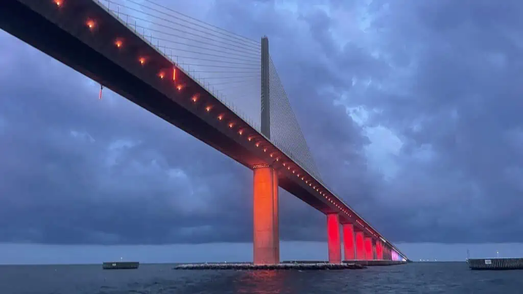 a bridge lit up with red and orange lights after sunset.