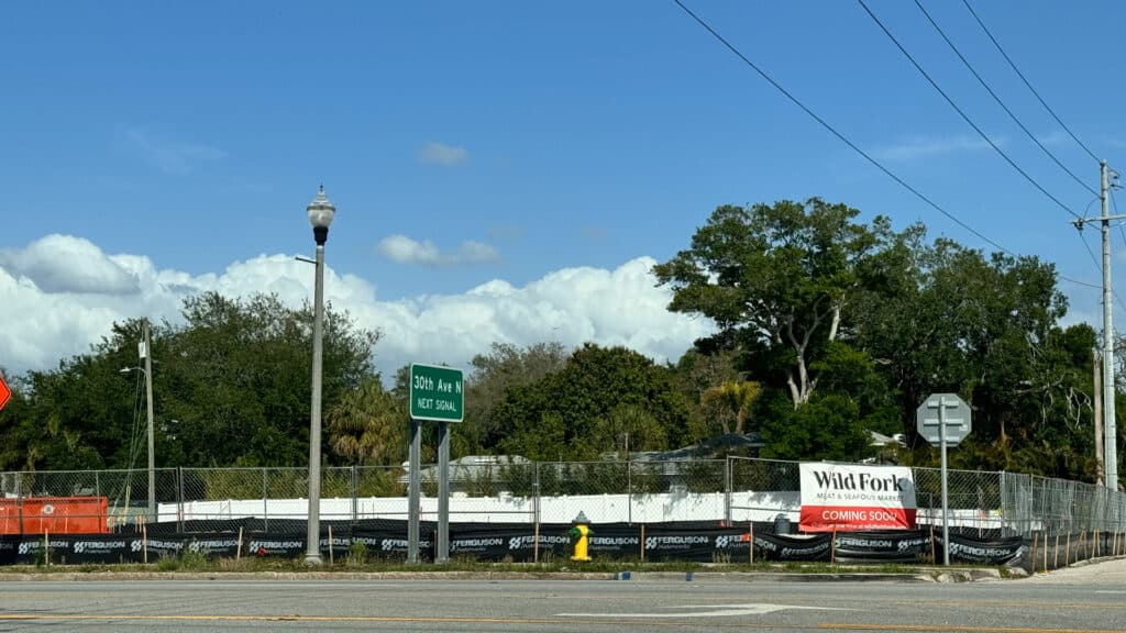 Street view of fenced lot with Wild Fork sign