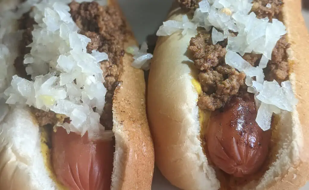 two hot dogs covered in chili