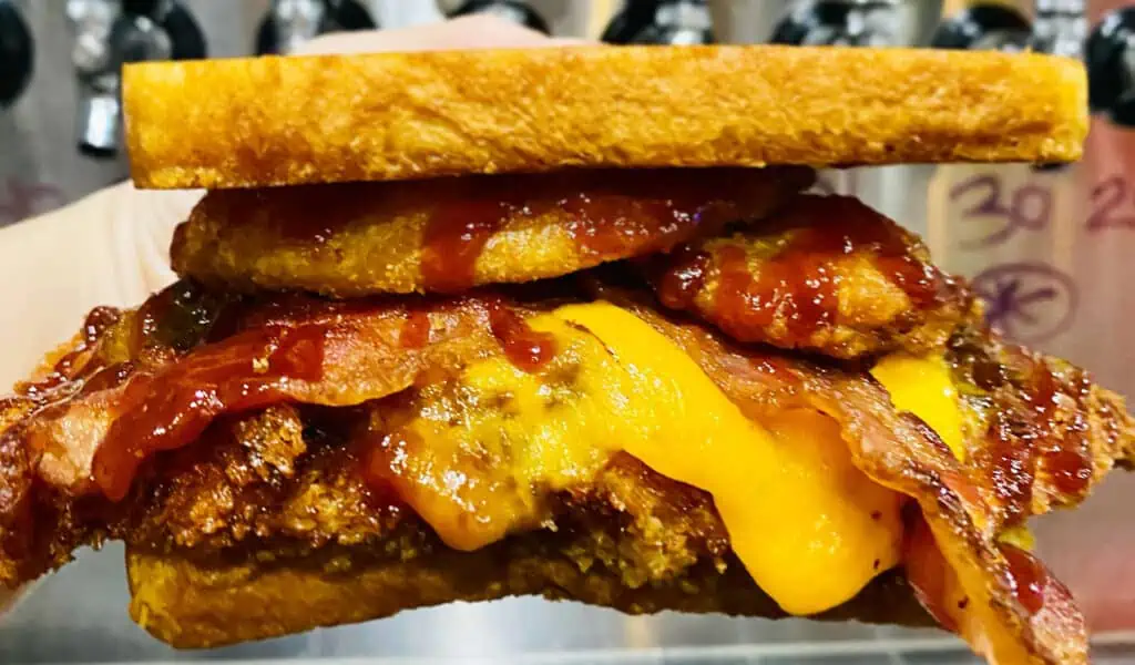 a large fried chicken sandwich with melty cheese dripping down the side