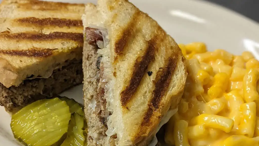a pressed sandwich on a plate with a side of Mac and cheese