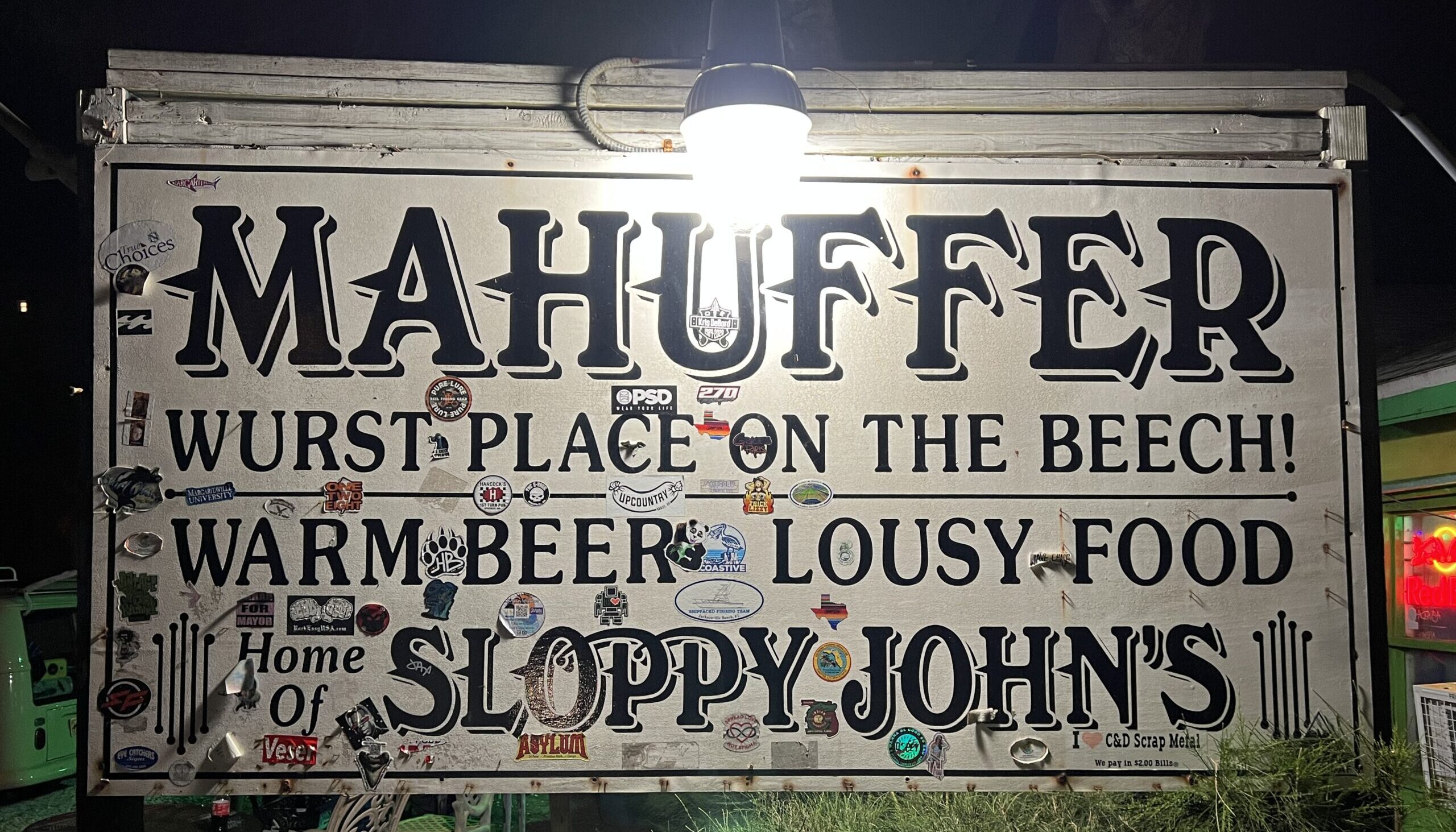 Sign saying "Mahuffer wurst place on the beech! Warm beer, lousy food. Home of Sloppy John"