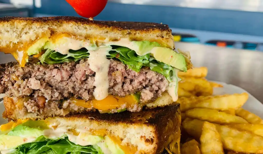 a burger with melty cheese and lettuce on top