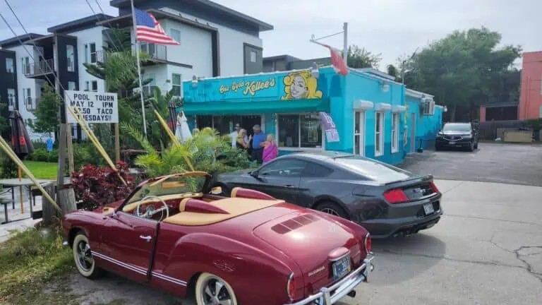 two sportscars in front of a bar with an American flag also waving