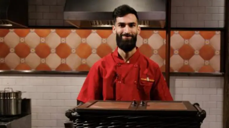 a chef in a red shirt poses on the set of a cooking show