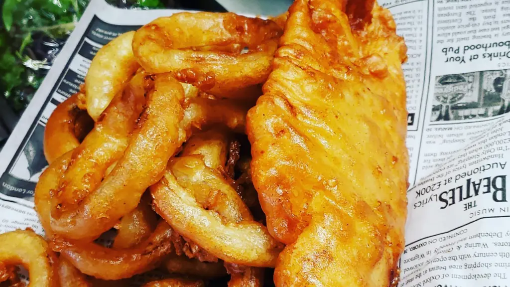 fried fish next to a side of fries on a latter covered with newspaper