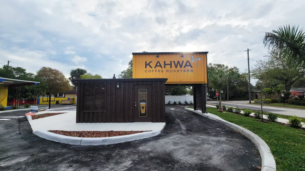 a drive thru coffee shop made of brown and yellow shipping containers