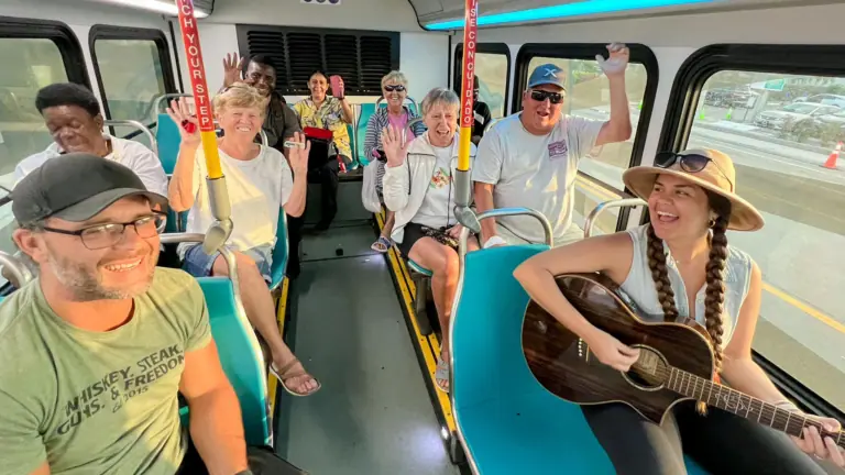 a group of people sit on a bus while a person plays the guitar