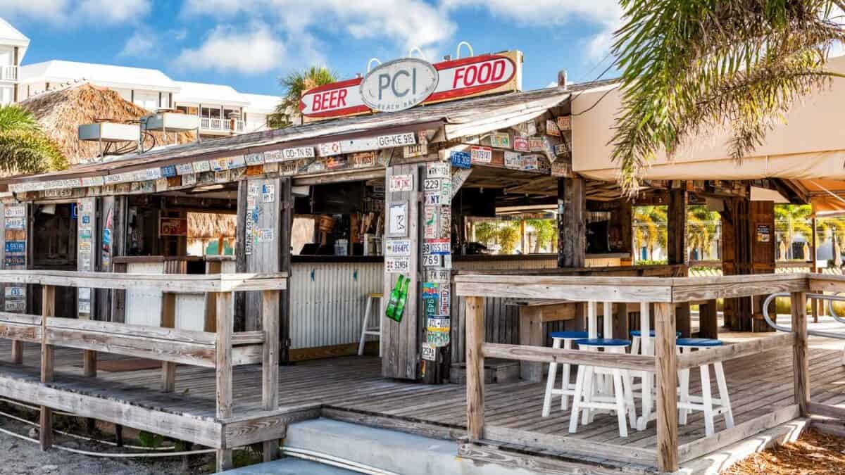 Beach Bar shack at Postcard Inn under palm trees on a sunny afternoon.